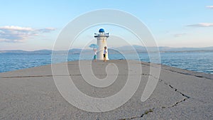 Young travelers playing with umberlla on pier near lighthouse. Europe travel with children. Family vacation background. Greece, is