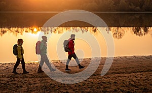 Young travelers walking near river at sunset