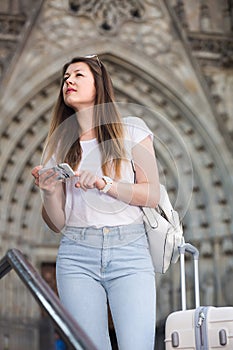 Young traveling girl searching for the direction using her phone in the town