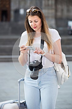 Young traveling girl searching for the direction using her phone in the town