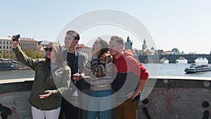 Young traveling group of friends standing on the bridge and taking a selfie