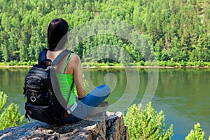 Young traveling woman sitting on the top of the mountain cliff.