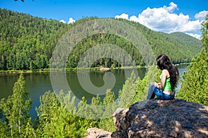 Young traveling woman sitting on the top of the mountain cliff.