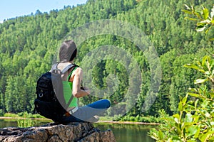 Young traveling woman sitting on the top of the mountain cliff.