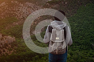 Young traveling woman on the top of the mountain cliff