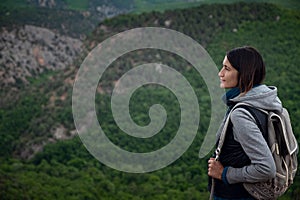 Young traveling woman on the top of the mountain cliff