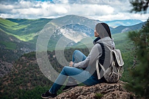 Young traveling woman on the top of the mountain cliff