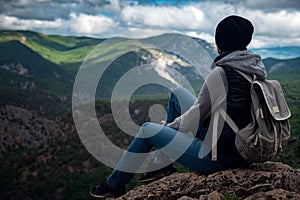 Young traveling woman on the top of the mountain cliff