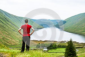 A young traveller man observing a lake in a deep valley covered photo