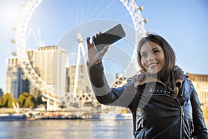 Young traveller woman talks a selfie in front of major sightseeing attractions in London, UK