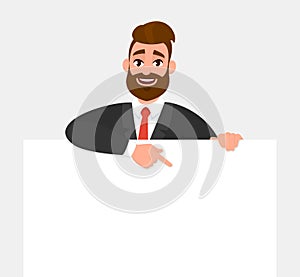 Young trendy businessman showing blank white poster and pointing finger. Happy hipster person holding empty banner.