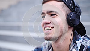 Young trendy man listen to music on smartphone sitting on the steps outdoor