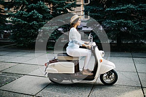 Young woman drinking takeaway coffee near her moped in the morning