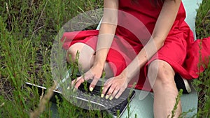 Young trendy woman typing keyboard. Girl using laptop outside.