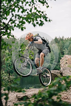 young trial biker performing stunt outdoors in front of