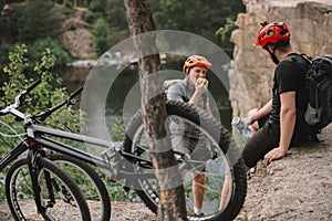 young trial bikers having rest on rocky cliff