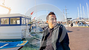 Young turkish tourist man smiling during sunset in Bodrum marina, Turkey. Sailing boats, sailor, and clear days