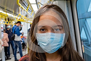 Young tween girl wearing surgical mask on subway