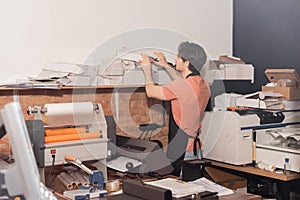 young typographer in apron reaching folded