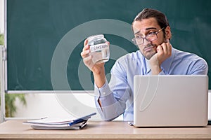 Young underpaid male teacher in the classroom photo