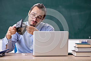 Young underpaid male teacher in the classroom photo