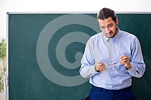 Young underpaid male teacher in the classroom photo