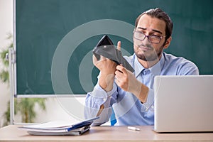 Young underpaid male teacher in the classroom photo