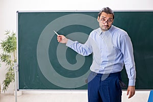 Young underpaid male teacher in the classroom photo