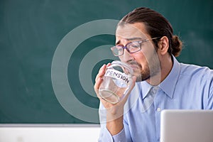 Young underpaid male teacher in the classroom photo