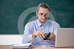 Young underpaid male teacher in the classroom photo