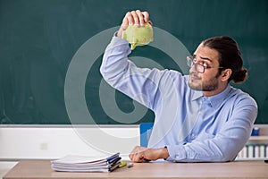 Young underpaid male teacher in the classroom photo