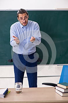 Young underpaid male teacher in the classroom photo