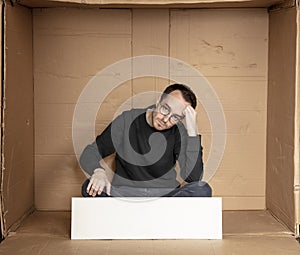 Young unemployed man holding a white board, a place for advertising, the idea of a cry for help