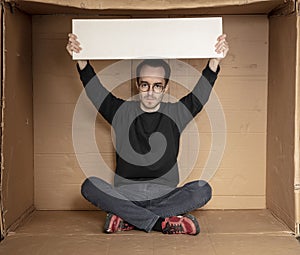 Young unemployed man holding a white board, a place for advertising, the idea of a cry for help