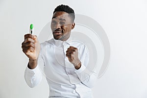 Young unhappy african american man looking at pregnancy test. Handsome sad man frustrated and having problems.