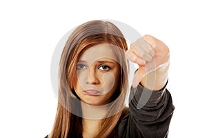 Young unhappy teenage woman showing thumb down