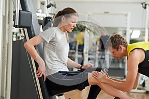 Young unhappy woman with leg injury at gym.