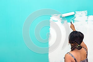 Young unidentifiable Asian woman painting wall with paint roller