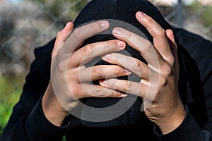 Young unidentifiable teenage boy holding hes head at the correctional institute