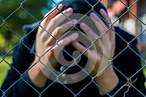 Young unidentifiable teenage boy holding hes head at the correctional institute ,conceptual image of juvenile delinquency