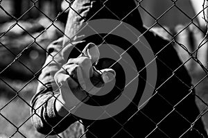 Young unidentifiable teenage boy holding the wired garden at the correctional institute in black and white