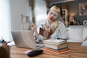 Young university student, college woman or girl, study for final exam at home. Young female learning and educate herself using