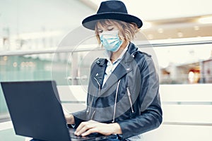 Young university student in mask using laptop indoors