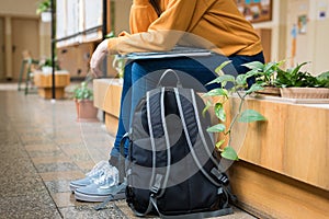 Young unrecognisable depressed lonely female college student sitting in the hallway at her school.