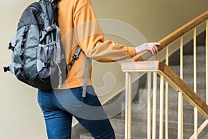 Young unrecognisable depressed lonely female college student walking up the stairs at her school. photo