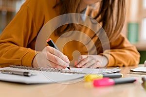 Young unrecognisable female college student in class, taking notes and using highlighter. Focused student in classroom. photo