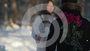 Young unrecognizable man holding flowers behind and waiting for his girlfriend