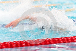 Young unrecognized man competing in freestyle swimming. Long exposure. Motion blur