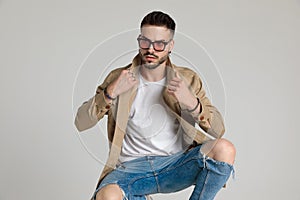 Young unshaved casual guy looking to side and fixing jacket