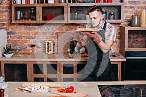 Young unskilled cooker scrutinizing pizza photo